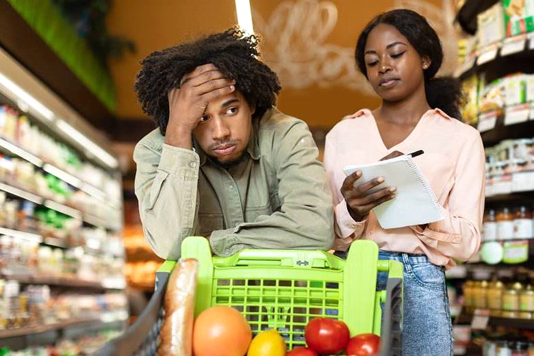 A worried couple with a shopping cart in a grocery store aisle