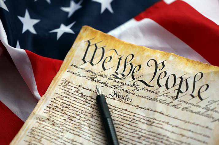The U.S. Constitution, â€œWe the People,â€ on an American flag with a pen